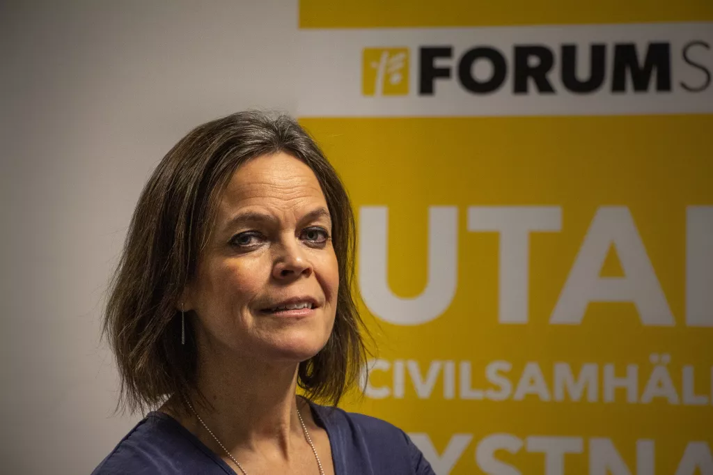 Anna Stenvinkel poserar framför roll-up:en där det står "Utan civilsamhället tystnar demokratin".