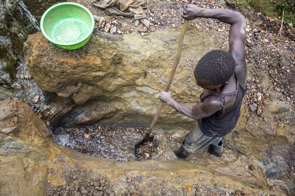 En man i kongo gräver efter guld i lera. 