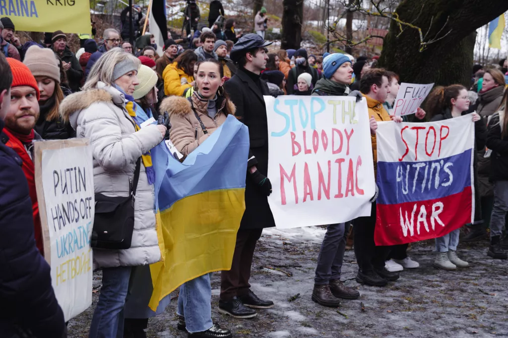 Människor demonstrerar med skyltar och Ukrainska flaggor