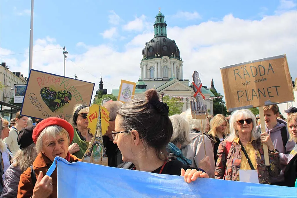 Demonstranter står med skyltar med budskap som rädda vår enda planet vid Odenplan i Stockholm.