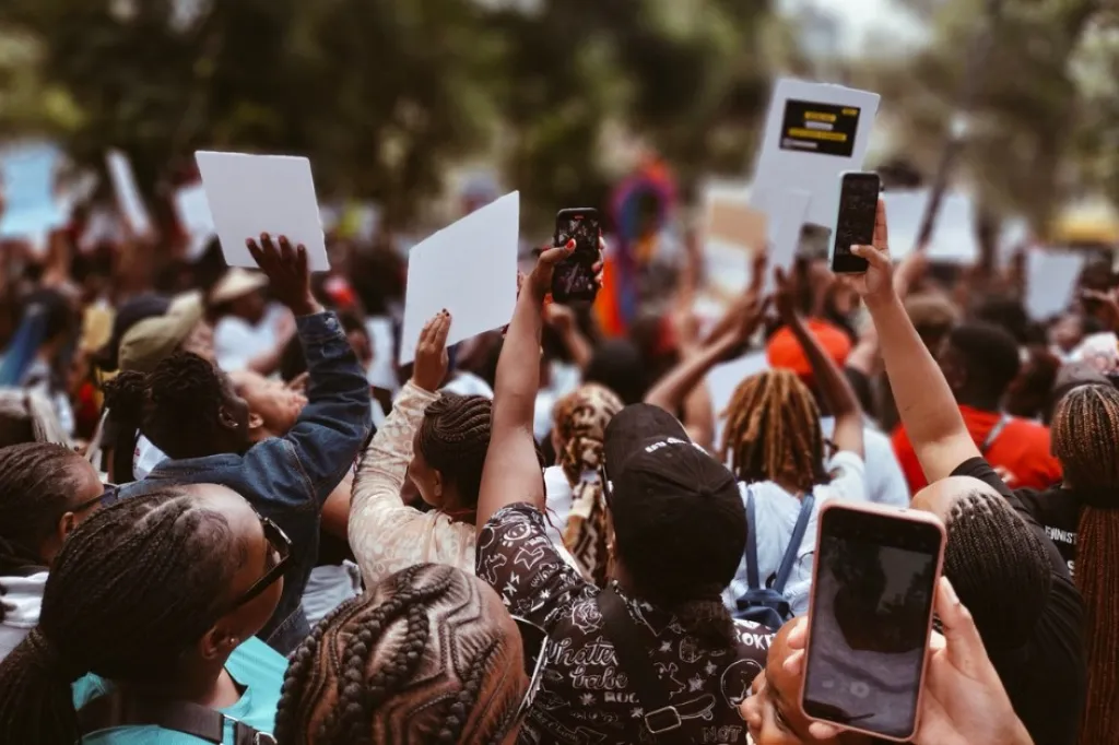 People walking in demonstrations holding signs and mobile phones.