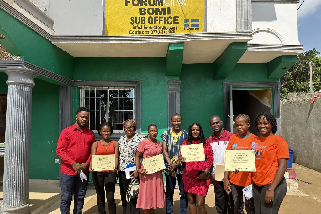 Participants standing outside an office building holding certificates