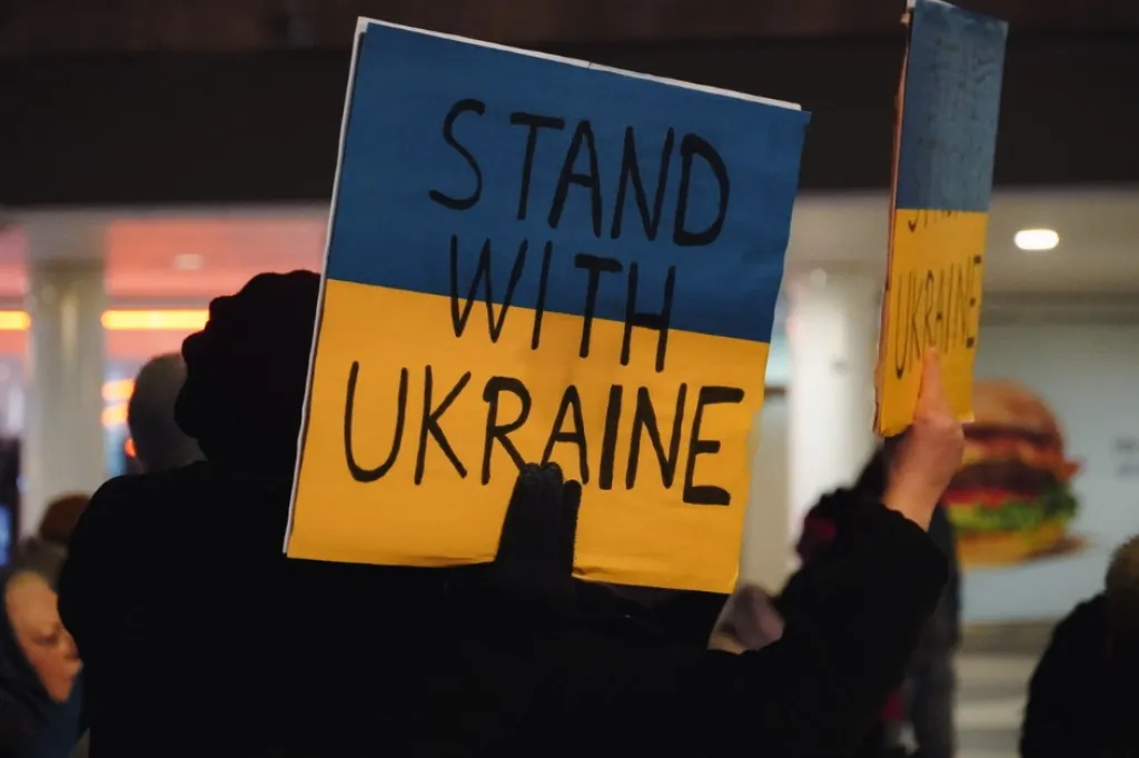 Demonstrationsskylt i blått och gult med texten stand with Ukraine.