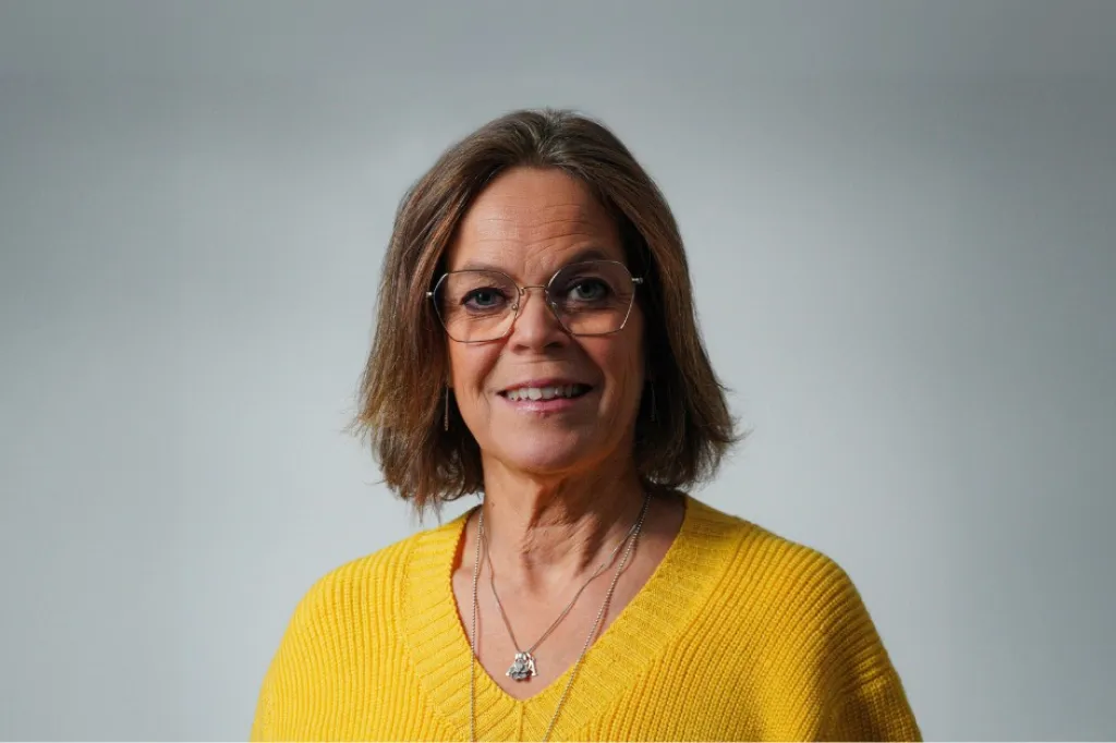 Anna ler mot kameran iklädd en gul tröja.