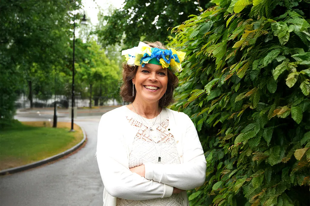 Anna stenvinkel ler mot kameran med en midsommarkrans i papper på huvudet.