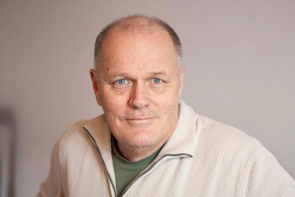 Göran ler in i kameran iklädd en vit tröja.