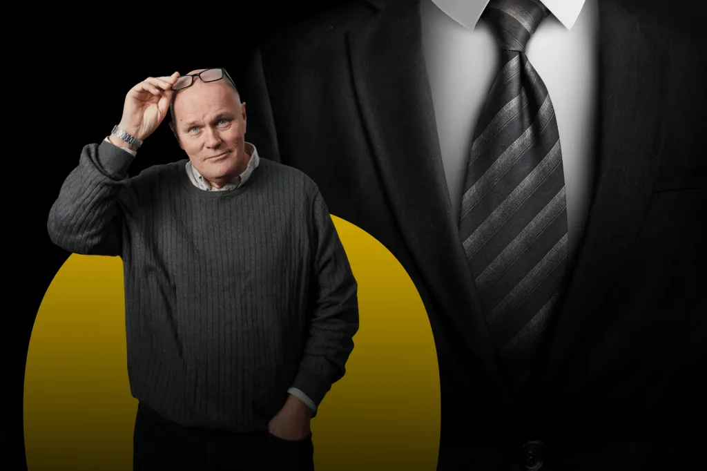 Kostym i grått med randig slips. I förgrunden står Göran och blickar in i kameran.