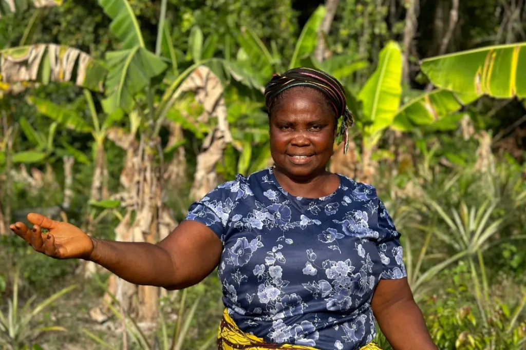 Kvinna i Liberia ler mot kameran och sträcker ut en hand.