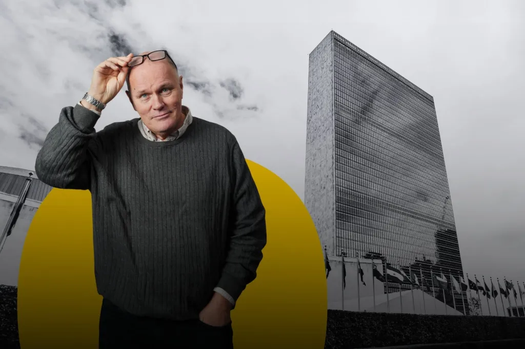 Göran Holmqvist i grå tröja. I bakgrunden syns FN skrapan i New York.