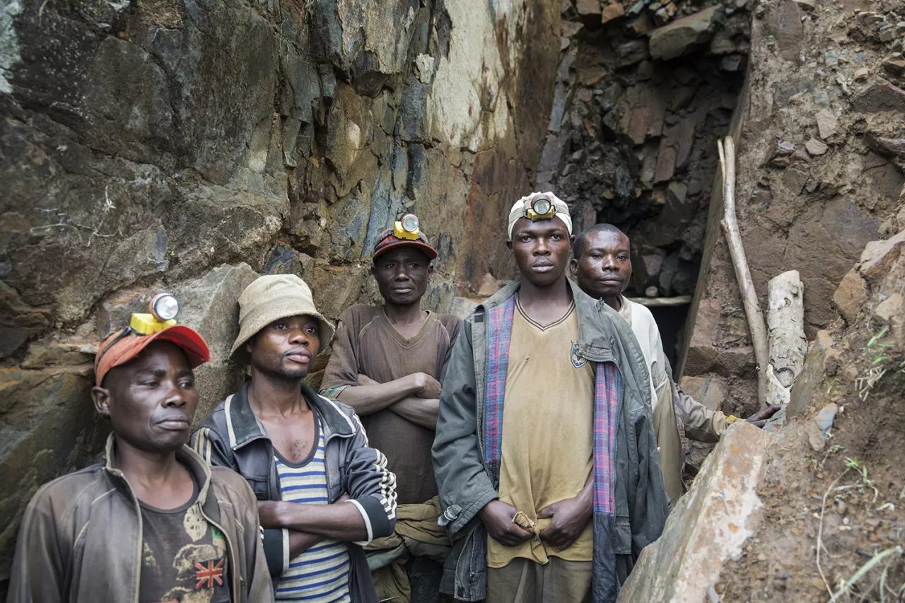 Group photo of exhausted miners at a mining entrance.