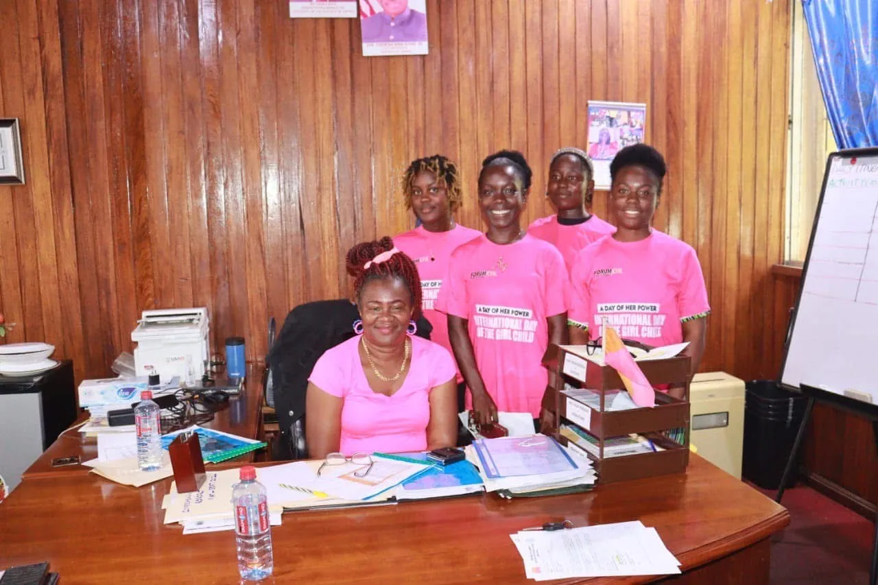 Five women in pink t-shirts with the text a day in her power are standing behind a deskdesk