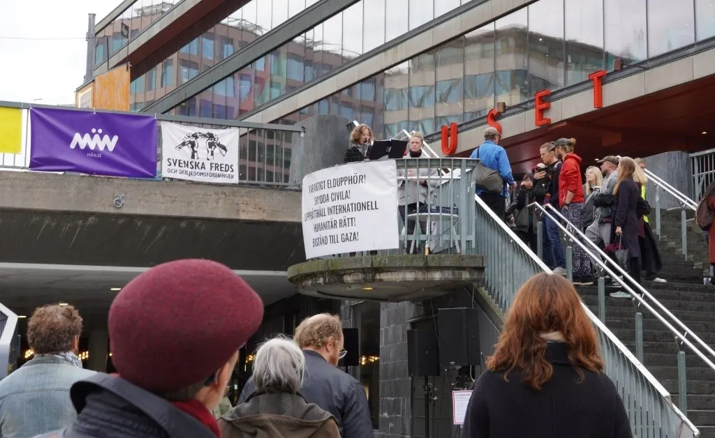 Människor läser namn ur pärmar under manifestationen på Sergels torg.