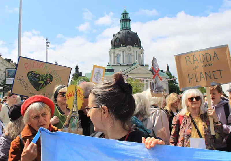 Demonstranter står med skyltar med budskap som rädda vår enda planet vid Odenplan i Stockholm.