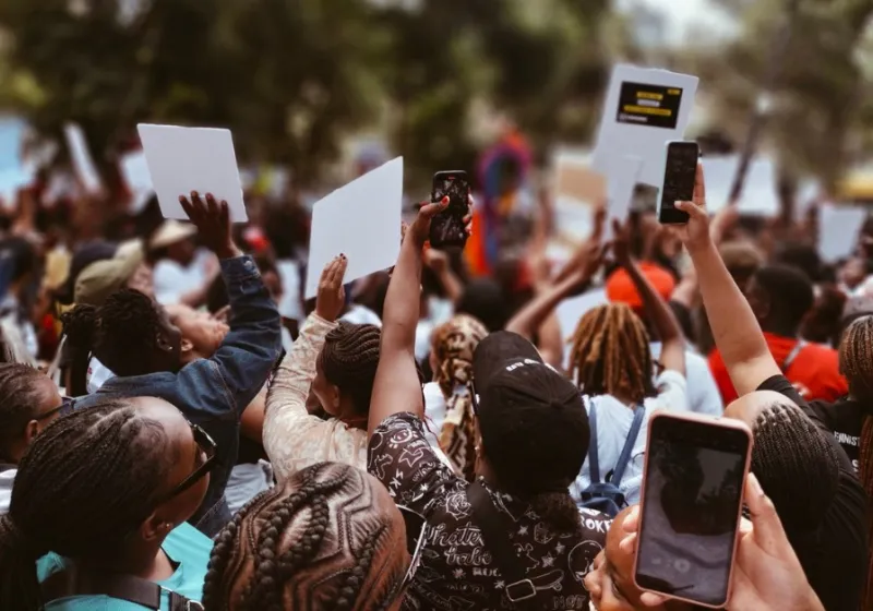 People walking in demonstrations holding signs and mobile phones.