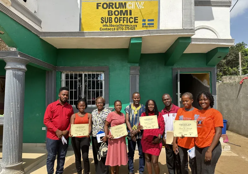 Participants standing outside an office building holding certificates