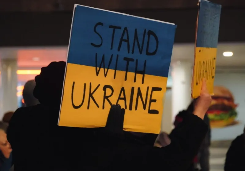 Protest sign in blue and yellow with the text stand with Ukraine.