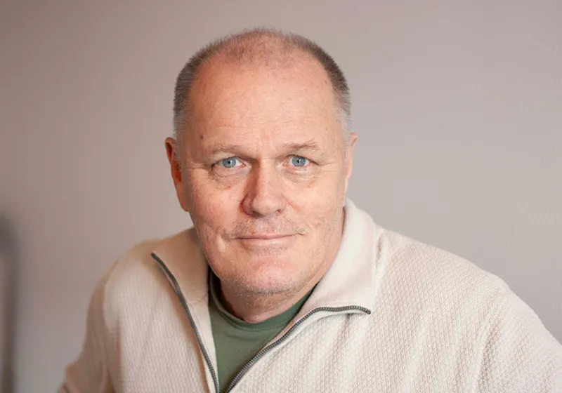 Göran ler in i kameran iklädd en vit tröja.