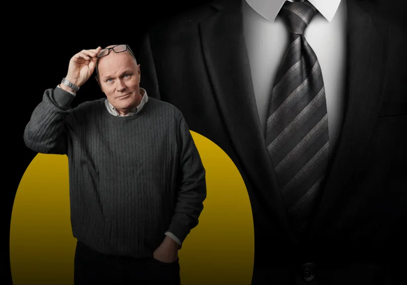 Kostym i grått med randig slips. I förgrunden står Göran och blickar in i kameran.