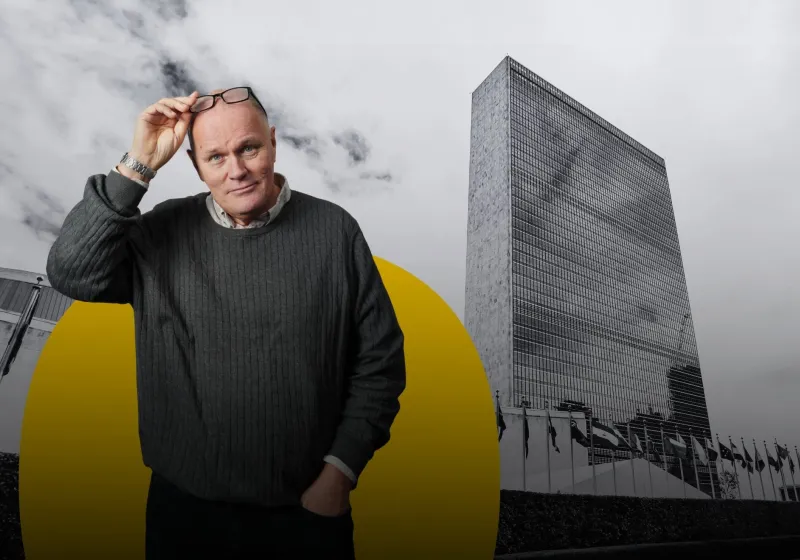 Göran Holmqvist i grå tröja. I bakgrunden syns FN skrapan i New York.