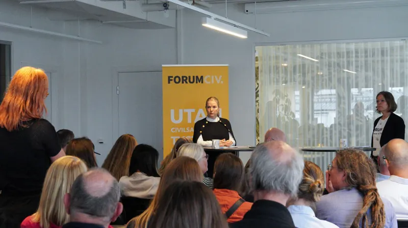 Diana Janse tar emot en fråga från en av ForumCivs medlemmar. Bredvid henne står Anna Stenvinkel generalsekreterare ForumCiv.