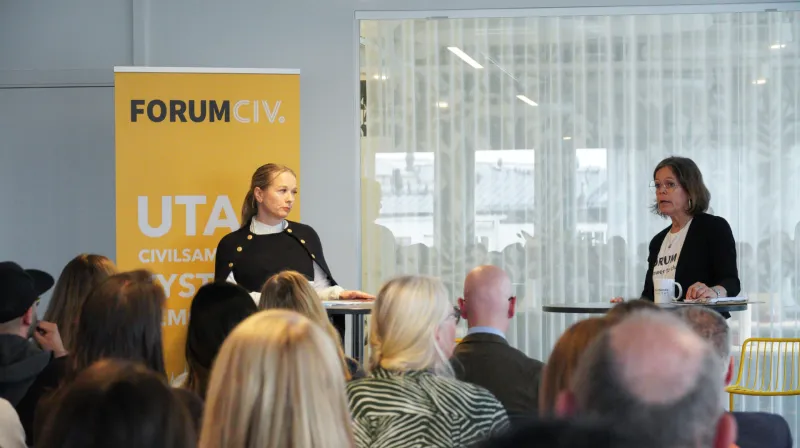 Diana Janse står framför en gul roll-up med ForumCivs logotyp. Till höger står Anna Stenvinkel.