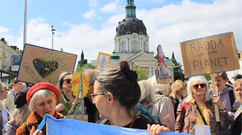 Demonstranter står med skyltar med budskap som rädda vår enda planet vid Odenplan i Stockholm.