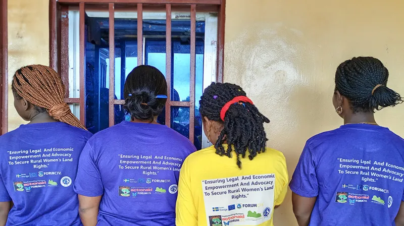 4 women have their back against the camera to show the text Empowering Rural Women through Legal and Economic Advocacy for Land Rights written on their purple t-shirts.