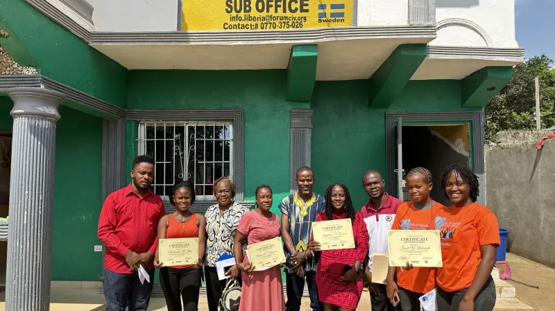 Participants standing outside an office building holding certificates