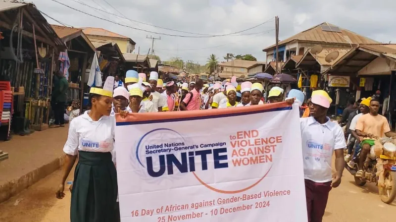 People marching with a banner that says unite against violence against women and girls