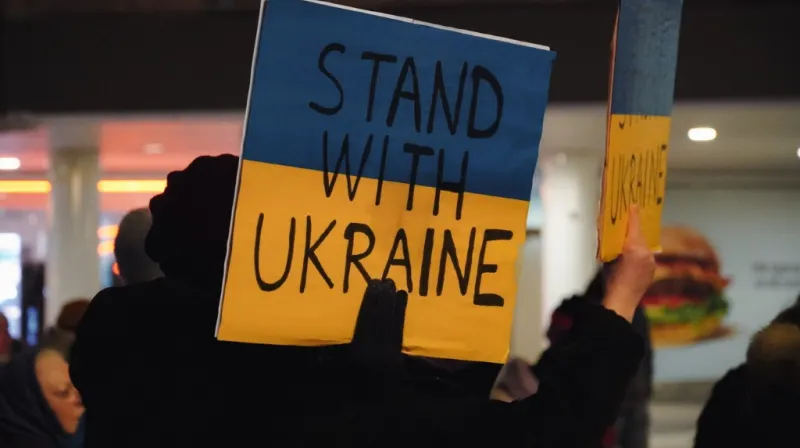 Protest sign in blue and yellow with the text stand with Ukraine.