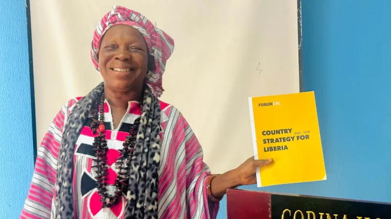 Woman holding the Liberia country strategy and smiling