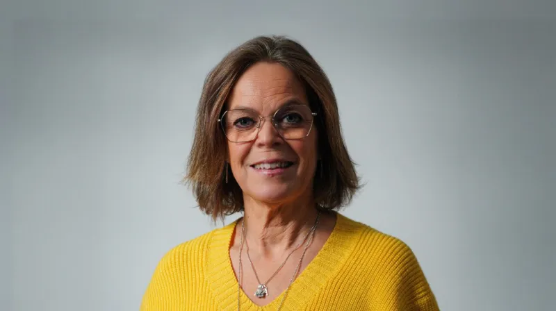 Anna ler mot kameran iklädd en gul tröja.