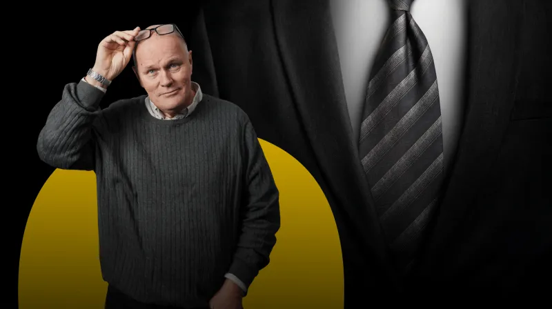 Kostym i grått med randig slips. I förgrunden står Göran och blickar in i kameran.